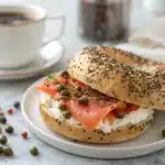 A toasted and sliced gluten-free bagel with cream cheese on a plate.