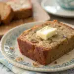 A warm slice of moist gluten-free banana bread with melting butter.