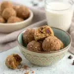 A bowl of finished gluten free protein balls, with one bite taken out to show the texture.