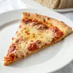 A perfect slice of pizza made with the gluten free pizza dough recipe, showing the chewy crust.
