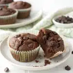 Gluten Free Chocolate Zucchini Muffin on a white plate, broken open to show the fudgy interior.