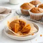 One gluten free pumpkin muffin broken in half to display its soft, moist crumb.