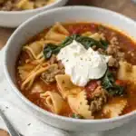 A perfect bowl of Gluten Free Lasagna Soup with a ricotta topping on a white background.