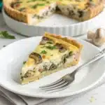 A perfect slice of homemade gluten free quiche with a rich mushroom and cheese filling on a white plate
