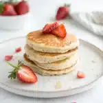 A small stack of two fluffy gluten free protein pancakes on a white background.