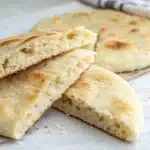 A close-up of a Gluten-Free Flatbread torn in half to show the soft, pillowy inside.
