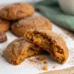 A close-up of a Chewy Pumpkin Cookie bent in half to show the dense, chewy inside.