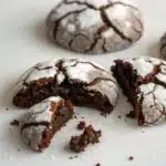 A close-up of a Gluten-Free Chocolate Crinkle Cookie broken to show the fudgy inside.